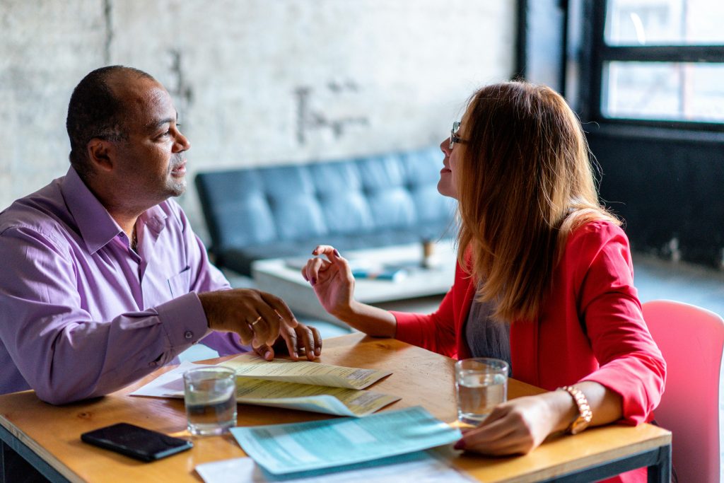 Professionals engaged in a collaborative meeting with documents in a contemporary office space.